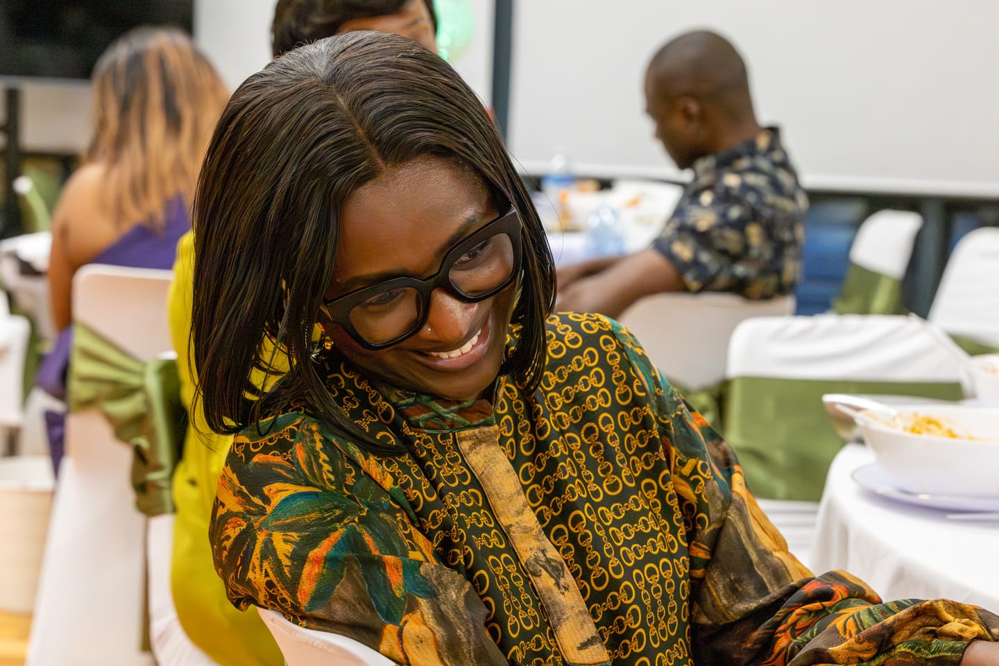 A guest in patterned green and gold glancing back over her shoulder, laughing